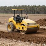 Rodillo compactador compactando suelo para la base de un galpón en el campo, con estacas de replanteo